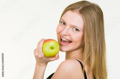 Photo: Beautiful Young woman with brackets eating apple Beautiful Young woman with brackets eating apple