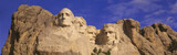 Photo: This is a close up view of Mount Rushmore National Monument against a blue sky. It shows the four faces of George Washington, Thomas Jefferson, Theodore Roosevelt, and Abraham Lincoln. This is a close up view of Mount Rushmore National Monument against a blue sky. It shows the four faces of George Washington, Thomas Jefferson, Theodore Roosevelt, and Abraham Lincoln.