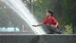 Boy touching a fountain on a summer day.