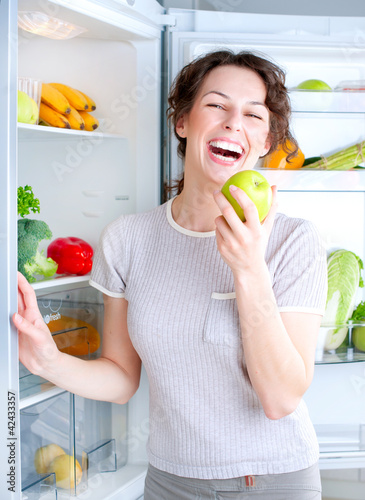 Photo: Beautiful Young Woman near the Refrigerator with healthy food Beautiful Young Woman near the Refrigerator with healthy food