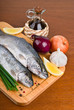 Fresh raw fish with herbs and spices on kitchen board