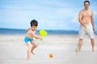 Father and son playing tennis on the beach