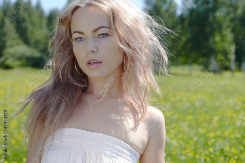 Foto : beautiful blond girl on green field with flowers beautiful blond girl on green field with flowers