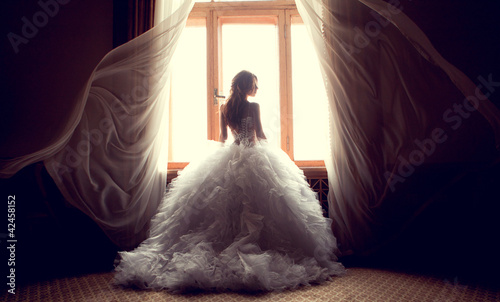 Photo: The beautiful bride against a window indoors The beautiful bride against a window indoors
