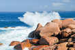 sea wave breaks against the pink granite rocks