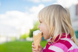 Photo: Adorable girl eat ice cream on green grass Adorable girl eat ice cream on green grass