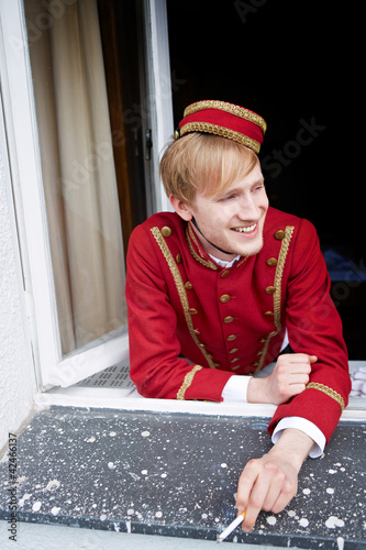 Photo: Page im Hotel raucht am Fenster Page im Hotel raucht am Fenster
