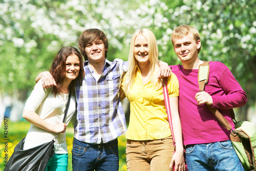 Photo: Group of four students in summer park outdoors Group of four students in summer park outdoors