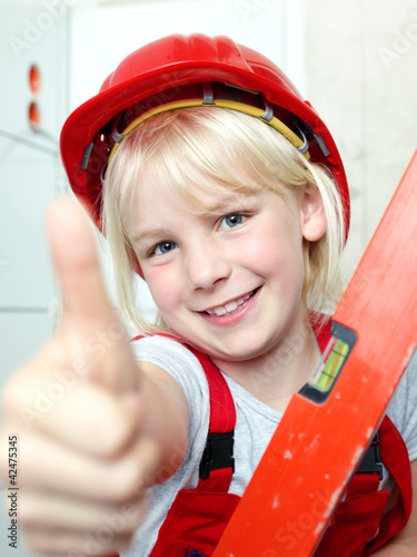 Foto: Little girl with helmet showing thumb up for building a house Little girl with helmet showing thumb up for building a house
