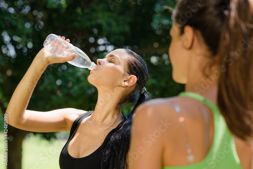 Foto: Two young women relaxing after fitness in park Two young women relaxing after fitness in park