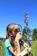 Little girl using magnifying glass examining field flowers