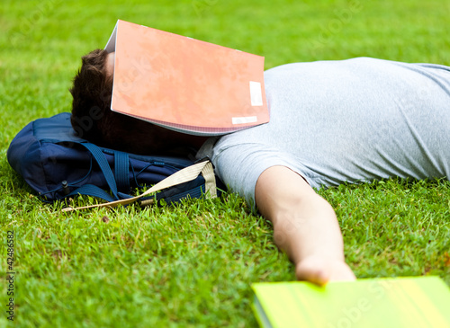 Foto: Tired student sleeping with a book over is face at the park Tired student sleeping with a book over is face at the park