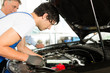Kunde und Mechaniker an Auto schauen unter Haube