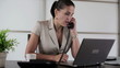 Young businesswoman working on laptop and talking in the office