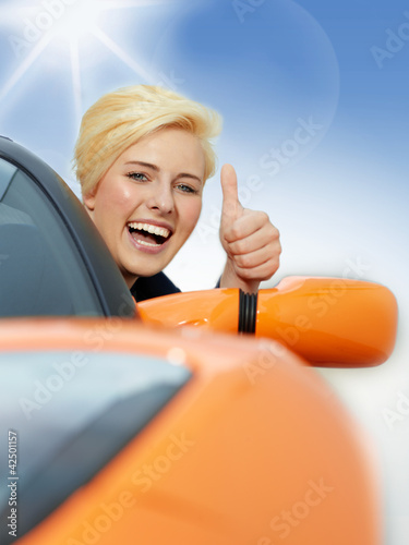 Foto: Beautiful 20s driving a roadster and shows thumb up Beautiful 20s driving a roadster and shows thumb up
