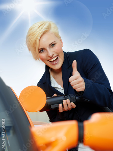 Foto: Woman has fun to load electrically powered car outdoors Woman has fun to load electrically powered car outdoors
