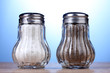 Salt and pepper mills on wooden table on blue background