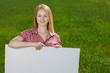 Young woman holding blank whiteboard, on grass background