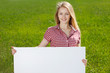 Photo: Young woman holding blank whiteboard, on grass background Young woman holding blank whiteboard, on grass background