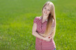Beautiful girl standing with folded hands over grass background