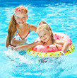 Foto: Children sitting on inflatable ring on water. Children sitting on inflatable ring on water.