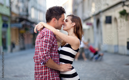 Photo: Young couple in love, hugging on the street. Selective focus. Young couple in love, hugging on the street. Selective focus.
