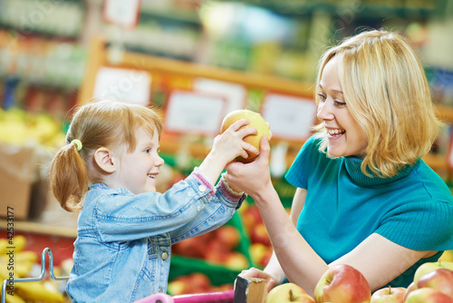 Photo: woman and little girl shopping fruits woman and little girl shopping fruits