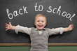 Cheerful smiling child stands at the blackboard. Looking at came