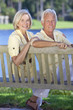 Senior Couple Sitting On Park Bench By Lake