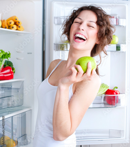 Photo: Beautiful Young Woman near the Refrigerator with healthy food Beautiful Young Woman near the Refrigerator with healthy food
