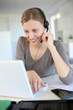 Young woman working from home with laptop and headset