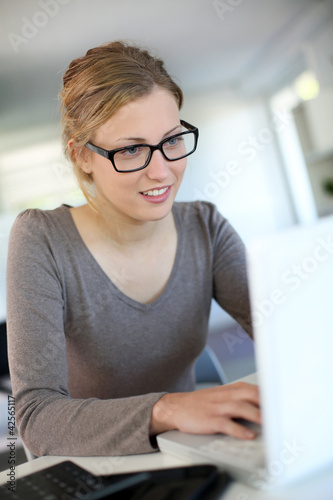 Foto: Beautiful young woman studying at home on laptop Beautiful young woman studying at home on laptop