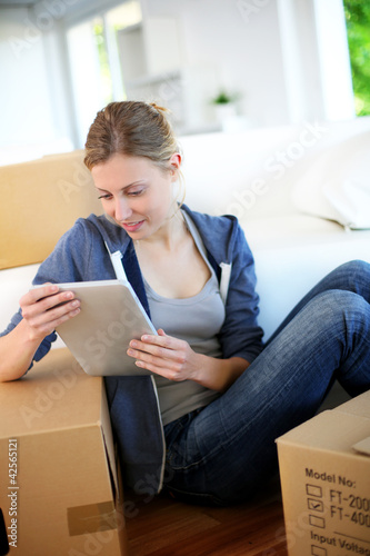 Photo: Young girl websurfing on tablet in new flat Young girl websurfing on tablet in new flat