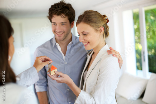 Foto: Happy young couple getting keys of their new home Happy young couple getting keys of their new home