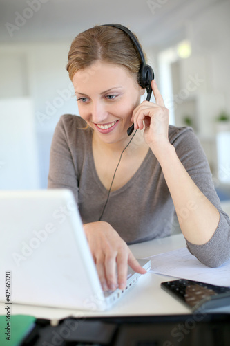 Photo: Young woman working from home with laptop and headset Young woman working from home with laptop and headset