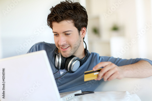 Photo: Young man buying music on internet with tablet Young man buying music on internet with tablet