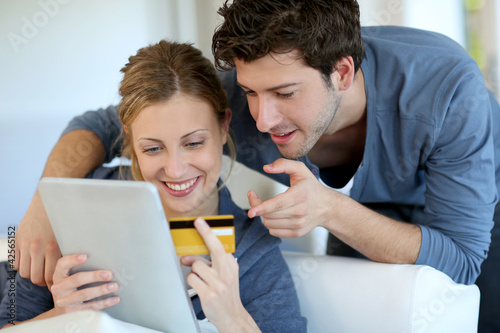 Photo: Young couple at home buying on internet Young couple at home buying on internet