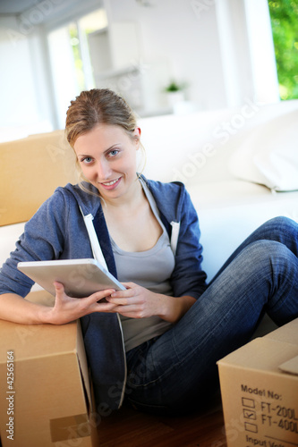 Photo: Young girl websurfing on tablet in new flat Young girl websurfing on tablet in new flat