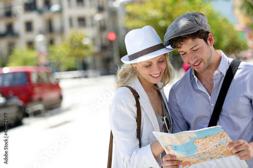 Photo: Trendy young couple in town with touristic map Trendy young couple in town with touristic map