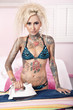 Portrait of young tattooed woman ironing in bedroom