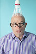 Portrait of senior man making face with shuttlecock on head