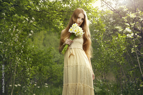 Foto: Portrait a beautiful young woman with flowers in the garden Portrait a beautiful young woman with flowers in the garden