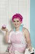 Portrait of happy young woman holding cupcake while ironing