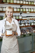 Foto: Portrait of a happy senior female employee holding spice jar in store Portrait of a happy senior female employee holding spice jar in store