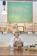 Portrait of a happy senior merchant with spice jar at counter in store