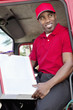 Young African American man sitting in delivery truck with box