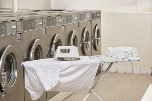 Photo: Ironing board with washing machines in Laundromat Ironing board with washing machines in Laundromat
