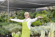 Portrait of a senior woman standing with arms outstretched in garden center