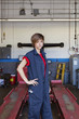 Portrait of a young female mechanic standing with hand on hip in car workshop
