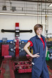 Happy young female mechanic with hands on hips in automobile repair shop
